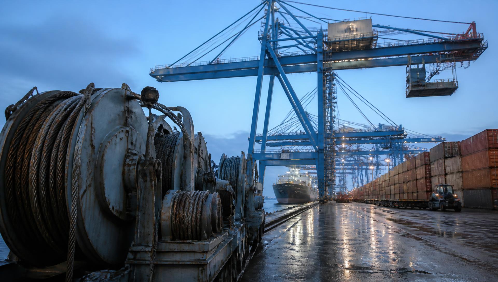 Container port gantry cranes and steel winch drums at blue hour