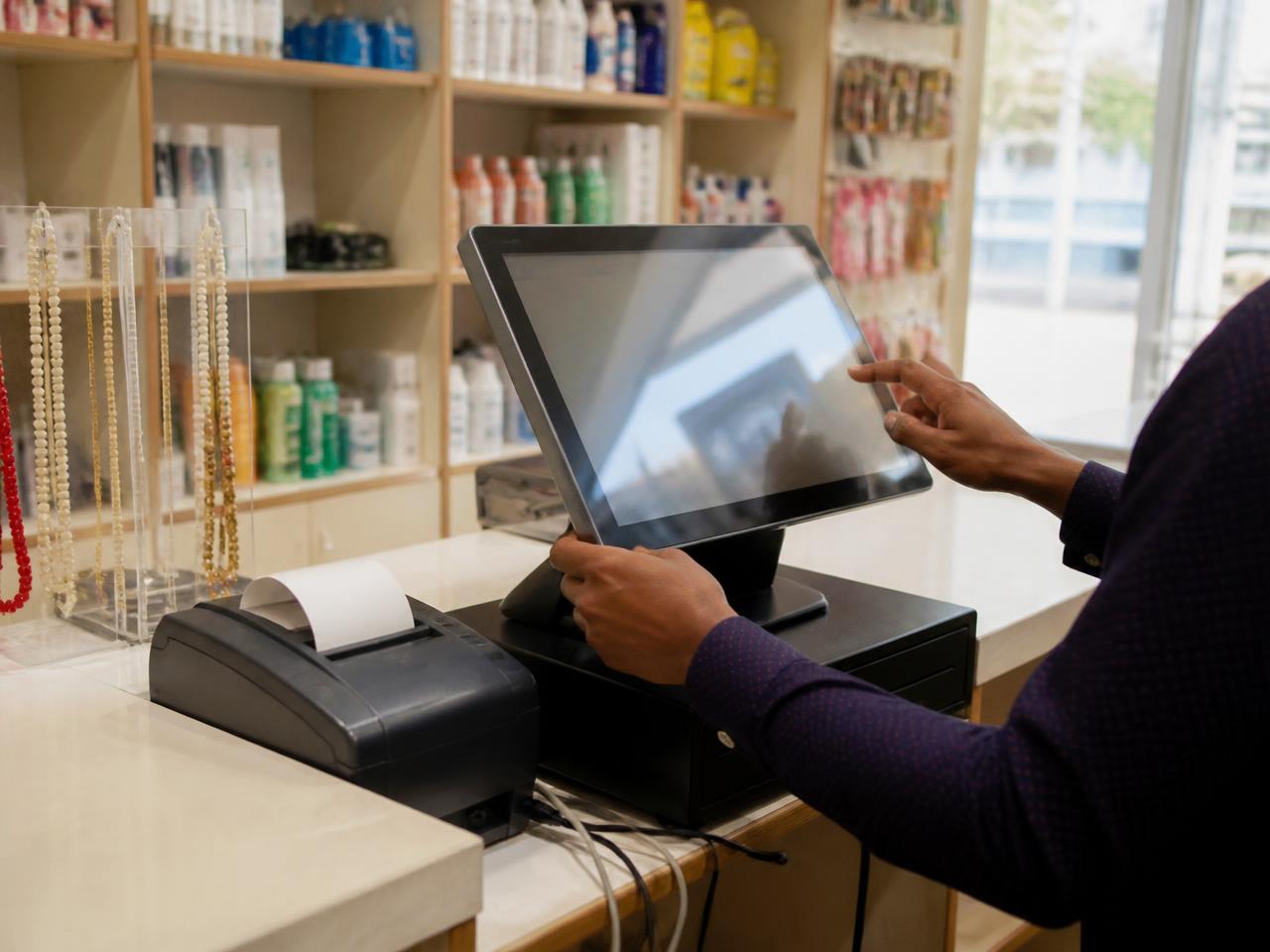 Shopkeeper using a point of sale terminal at a retail counter